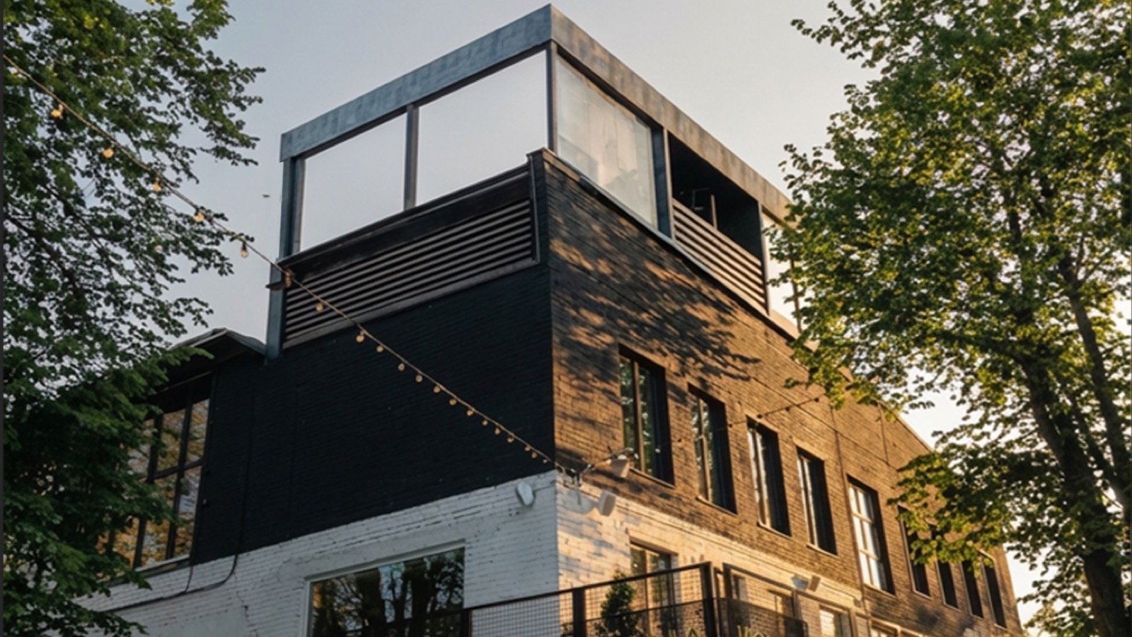 The Loft Links building at sunset, with the glass rooftop room above the brick façade